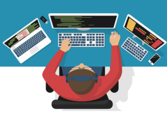Software engineer at computer desk working on program design.