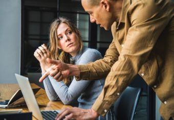 a man and a woman discussing their work on a laptop