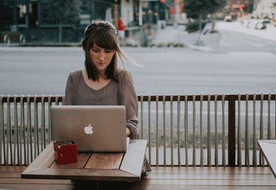 A woman uses a laptop while sitting on a patio