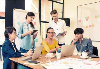 A project manager discusses a project with her team, who surround her on both sides.