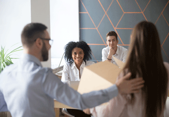 Two men and a woman welcome their new colleague to the office