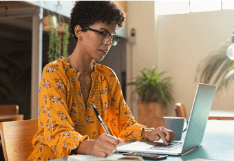 A woman in an orange top wearing glasses puts the finishing touches to her cover letter