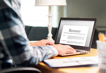 man sitting at a table on his laptop and adjusting his resume format