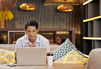A job applicant contemplates his resume on his laptop while drinking coffee.