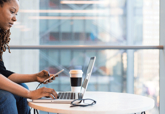 A lady writes a cover letter using her laptop in front of a window