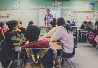 A teacher instructs a class of students using a digital whiteboard.