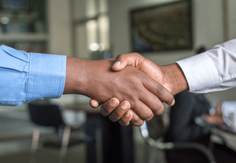 An employer and new hire shake hands after agreeing on the salary requirements proposed in the applicant's cover letter.