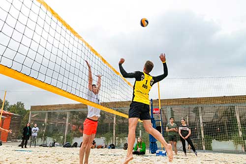 Man spikes a volleyball at the beach, volleyball is an example of an extracurricular activity you can put on your resume