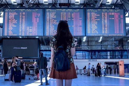 how to include study abroad on resume concept, airport photo of a young woman traveling to her study abroad destination
