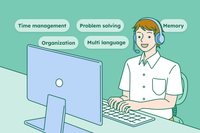 A receptionist wearing a white shirt is sitting down and speaking to a customer on the phone while working on his laptop, showcasing his receptionist skills